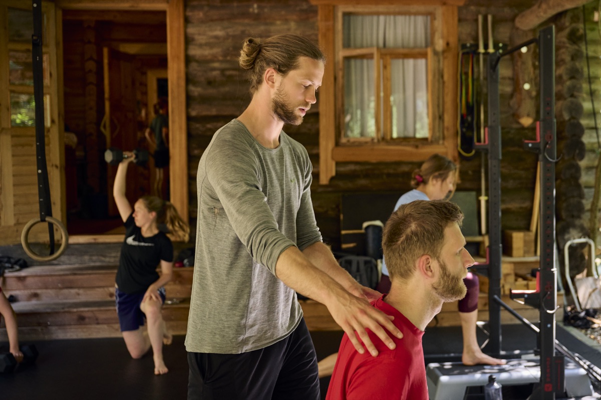 Michel Lüers korrigiert einen Klienten im Trainingshaus, im Hintergrund trainieren andere.